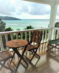 einen Tisch und Stühle auf einem Balkon mit Meerblick in der Unterkunft Seychelles Yellow Petals in Anse Boileau
