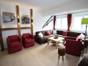 un soggiorno con divano e sedie rosse di Alpensteinbock Mauterndorf I a Mauterndorf