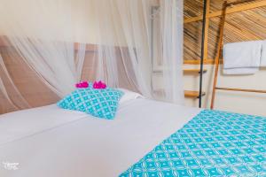 a bed with two blue pillows on top of it at Casa de la Gente Nube in Puerto Escondido