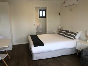 a bedroom with a white bed with black and white pillows at Lunar Cabins in Parkes