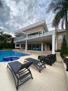 a large house with a swimming pool and two chairs at Cómoda Casa Finca con Piscina - San Jerónimo, Ant in Medellín