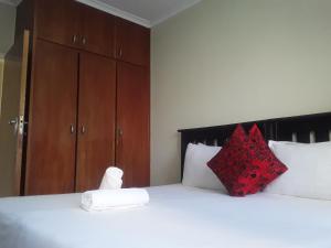 um quarto com uma grande cama branca com almofadas vermelhas em Kuyasa guesthouse em Mthatha