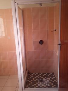 uma casa de banho com um chuveiro e piso em azulejo em Kuyasa guesthouse em Mthatha