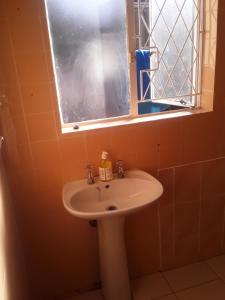 baño con lavabo y ventana en Kuyasa guesthouse, en Mthatha