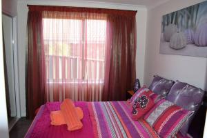 a bedroom with a pink bed with a cross on it at LILLI PILLI SUBLIME at the Beach - Family & Dog Friendly in Batemans Bay