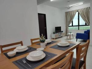 uma sala de jantar com uma mesa com pratos e cadeiras em Cozy Condo at Melaka Top Hill, 7-9pax em Ayer Keroh