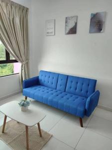 a blue couch in a living room with a table at Cozy Condo at Melaka Top Hill, 7-9pax in Ayer Keroh