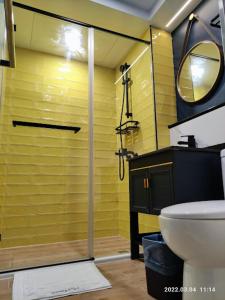 a bathroom with a shower with a toilet and a yellow wall at 18世紀普魯士藍現代寓所Prussian Blue Inn工業風 in Kaohsiung