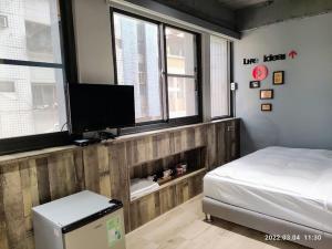 una camera da letto con un letto e una TV a schermo piatto di 18世紀普魯士藍現代寓所Prussian Blue Inn原愛迪亞旅社 a Kaohsiung