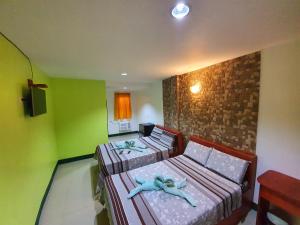 two beds in a room with green walls at Aosmec Square Hotel in Mactan
