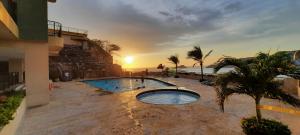 a swimming pool in front of a building with the sunset at El Peñon del Rodadero - Apto 1303A in Santa Marta
