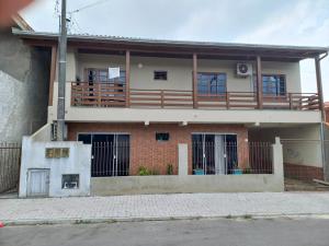 a house with a balcony on top of it at Hospedom Mazzoca 02 , WC compartilhado in Itapema