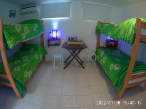 プエルト・ピラミデスにあるCOMPLEJO ALOHAの二段ベッド2台とテーブルが備わる客室です。