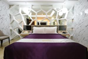 a bedroom with a purple bed and white walls at W3 MOTEL in Luzhu