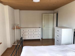 a bedroom with a white bed and a dresser at Simple flat in the centre of Burgdorf - 72 m2 with private parking in Burgdorf