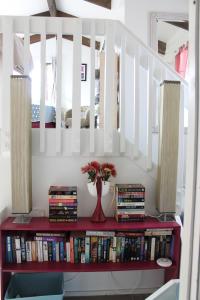 a red book shelf with books and a vase of flowers at Brockies B n B in Rawene