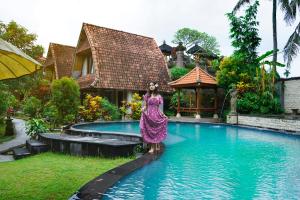 a woman in a dress standing next to a swimming pool at Abangan Bungalow in Ubud