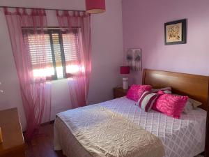 - une chambre avec un lit doté d'oreillers roses et d'une fenêtre dans l'établissement Nazaré Villa North Wave, à Nazaré