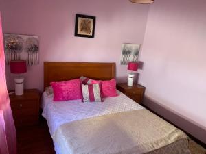 - une chambre avec un lit avec des oreillers roses et 2 lampes dans l'établissement Nazaré Villa North Wave, à Nazaré