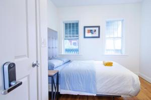 a white bedroom with a bed and two windows at 4BR 1,5BH Comfy Newly Renovated Apt in Boston