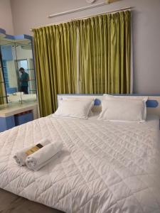 um quarto com uma cama branca com uma toalha em PRAVESH VILLA em Pondicherry
