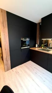 a kitchen with black walls and a wooden floor at Mazurski apartament in Ostróda