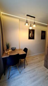 een eetkamer met een tafel, stoelen en verlichting bij Mazurski apartament in Ostróda