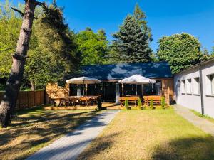 a patio with tables and umbrellas in a yard at Domki Skowronki in Kąty Rybackie