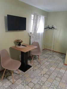 スーズダリにあるKupets Holiday Homeのテーブル、椅子2脚、テレビが備わる客室です。