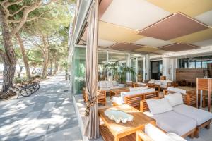 an outdoor patio with tables and chairs and windows at Hotel Europa Lignano in Lignano Sabbiadoro