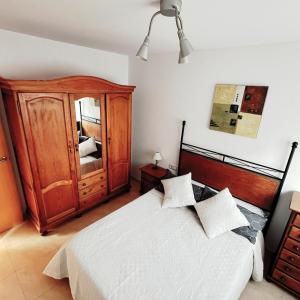a bedroom with a large bed and a wooden cabinet at APARTAMENTO EN SEGUNDA LINEA DE MAR, WIFI & A.C in Cubelles
