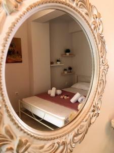 Un espejo que refleja un dormitorio con una cama dentro. en Pink Rose Apartment, en Nea Peramos