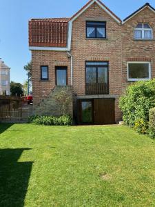 a brick house with a lawn in front of it at VILLA MICHRY Koksijde 4 adultes 2 enfants proche digue et centre in Koksijde