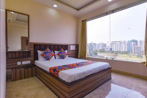 Schlafzimmer mit einem Bett und einem großen Fenster in der Unterkunft FabExpress Sunshine in Gauripur
