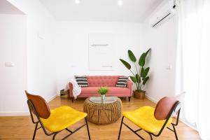 a living room with a pink couch and chairs at Apartamentos Durán Tirso de Molina in Merida