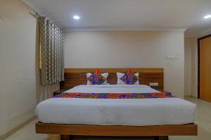 1 dormitorio con 1 cama grande y almohadas coloridas en FabHotel Pishori en Indore