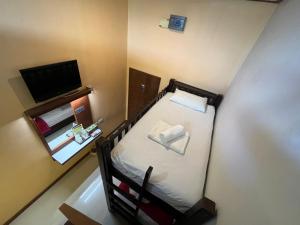 Habitación pequeña con cama y TV. en First and Frang Hotel - Koh Phangan en Thongsala