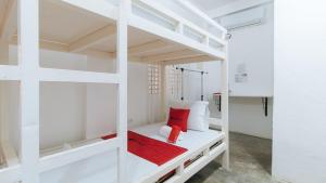 Cette chambre comprend un lit superposé blanc avec un oreiller rouge. dans l'établissement RedDoorz @ Camp Saint John Hotel La Union, à San Juan