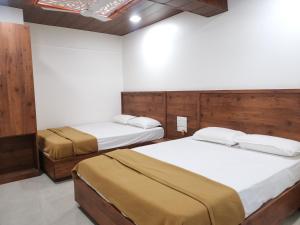 Duas camas num quarto com paredes brancas em Mahalaxmi Executive em Colhapur