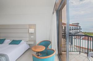 a bedroom with a bed and a table and a balcony at Anmaria Beach Hotel & Spa in Ayia Napa