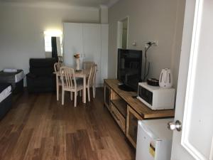 a living room with a television and a table with a microwave at Blue Pelican Motel in Tweed Heads