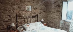 a bedroom with a bed and a stone wall at A Casa das Augas in Mondoñedo