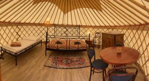 a yurt with a bed and a table and chairs at Öko Kemping és Glamping Tiszadada in Tiszadada