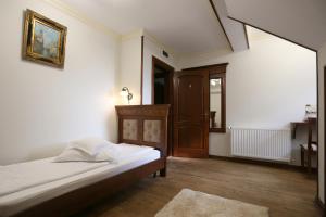 Schlafzimmer mit einem Bett mit weißer Bettwäsche und Holzböden in der Unterkunft Pensiunea Trei Pini in Seini