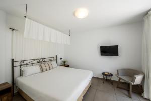 a bedroom with a white bed and a chair at Aliathon Aegean in Paphos City