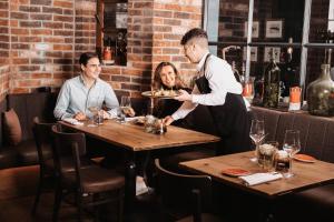 a man serving a woman at a table in a restaurant at FAVORITE Parkhotel I Spa - Business - Fine Dining in Mainz