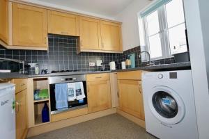 a kitchen with a washer and a washing machine at The Coach House near Swanpool, Falmouth, Cornwall. in Falmouth