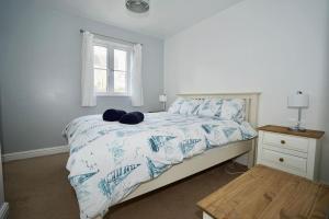 ファルマスにあるThe Coach House near Swanpool, Falmouth, Cornwall.のベッドルーム1室(青と白のシーツが敷かれたベッド1台、窓付)