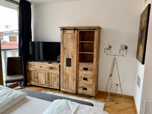 a bedroom with a television and a wooden cabinet at Modernes Apartment An der Frauenkirche II in Dresden +29 photos