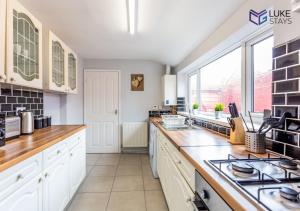 a kitchen with white cabinets and a large window at Luke Stays - Nora Street in Pallion